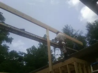 Carpenter setting a ridge beam over a new addition frame — Ice Dam Removal by Roofing Brothers in Milltown
