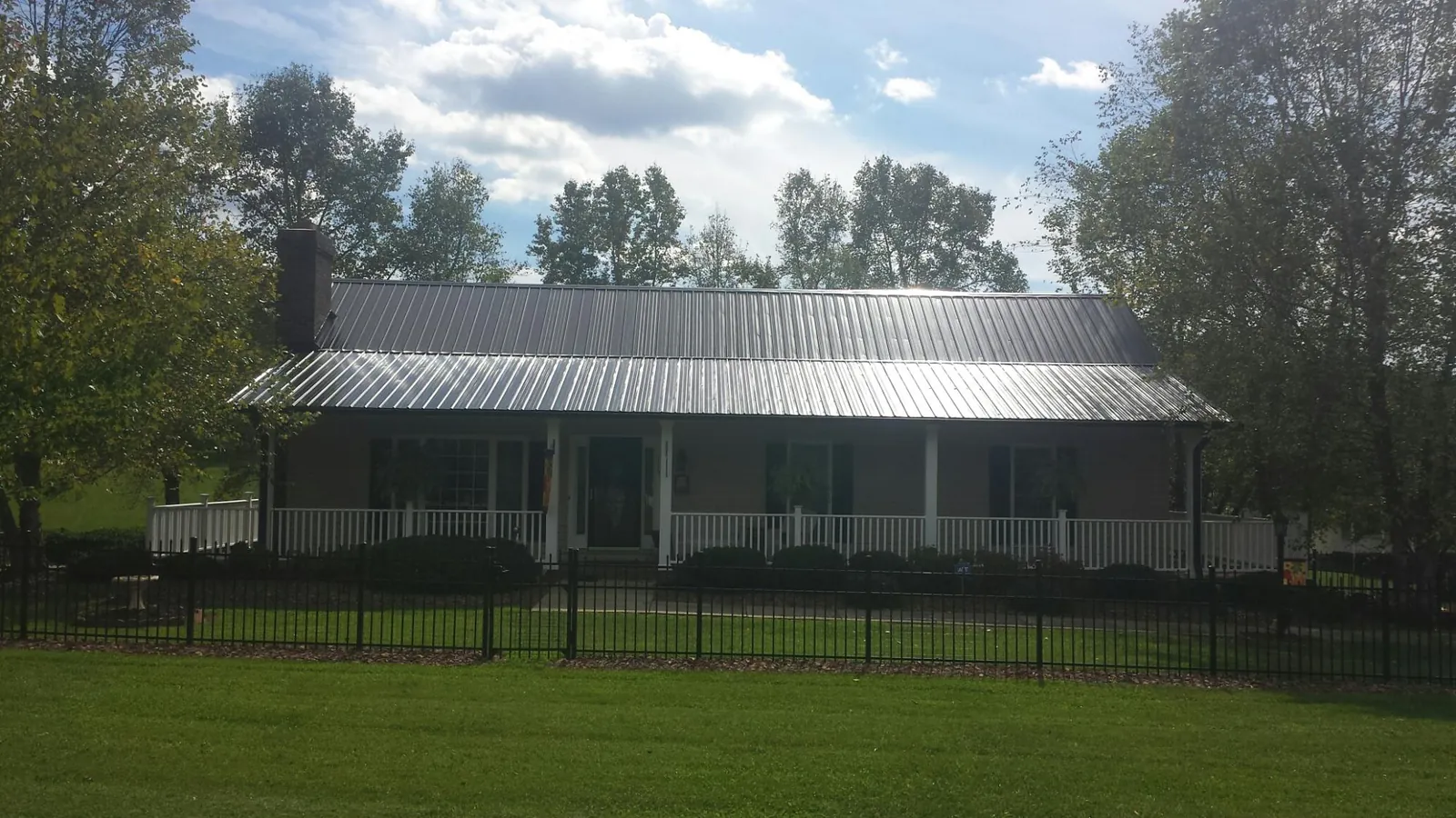 Gray metal roof on a brick ranch with a full width front porch — Gutter Guard Installation work by our crew in Milltown
